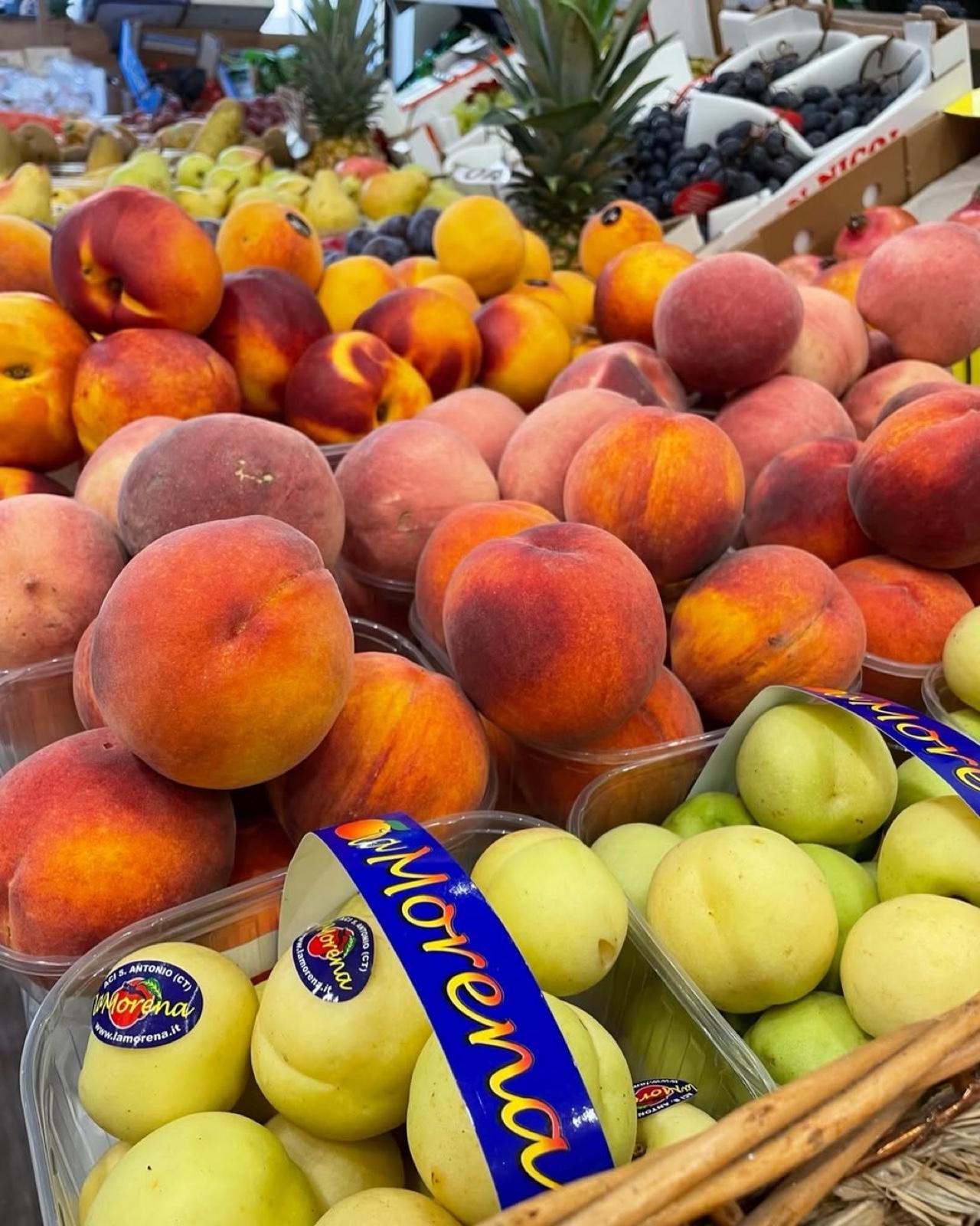 Il banco della frutta di Fruttiamo con pesche, nettarine e ananas